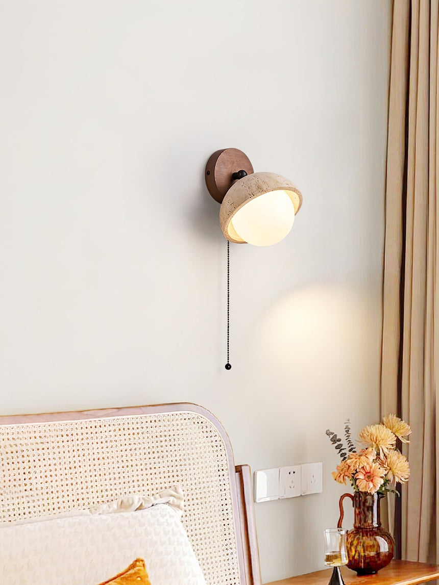 Single dome lit beside a cane headboard above a vase of dried flowers