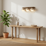 Two domes lit above a long wood console with potted plants either side