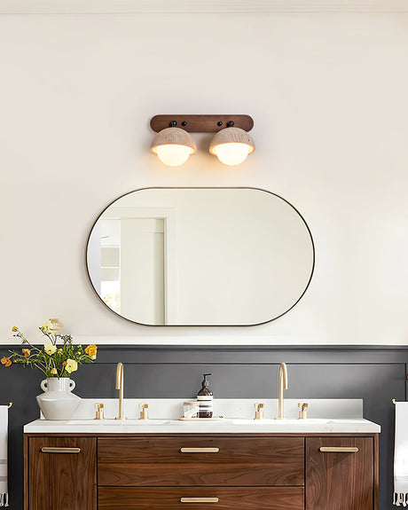 Two domes lit above an oval mirror on a dark wall over a wood vanity