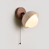 The pull chain hanging from the single dome fitting against a pale wall