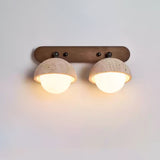 Two travertine domes on a walnut bar, both orbs lit warm below the stone