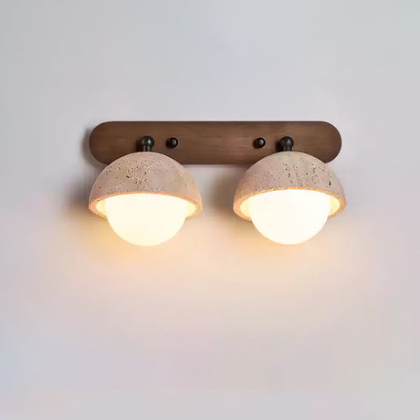 Two travertine domes on a walnut bar, both orbs lit warm below the stone