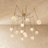 Alabaster globes lit on long brass arms that curve down from a central plate