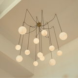 The fitting on brass arms against a ceiling corner, globes at several heights