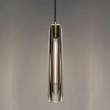 A slim copper and glass pendant lit against a dark painted wall