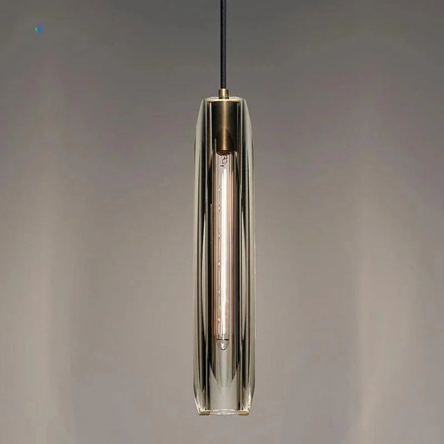 A slim copper and glass pendant lit against a dark painted wall