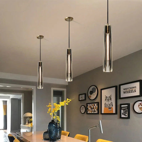 Two slim copper pendants lit beside framed artwork above a cabinet
