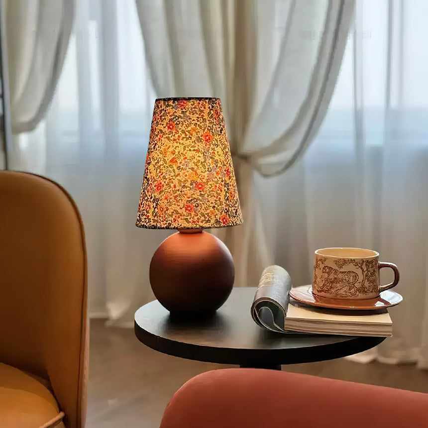 Floral shade lamp lit on a round tray table beside a cup