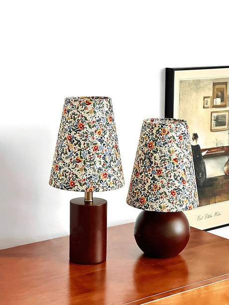 Two floral shade lamps lit together on a wood sideboard