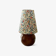 Floral shade lamp on a wood sphere base against a plain ground