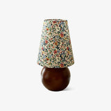 Floral shade lamp on a wood sphere base against a plain ground
