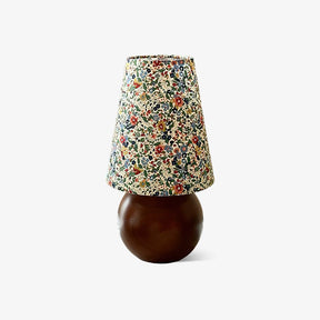 Floral shade lamp on a wood sphere base against a plain ground