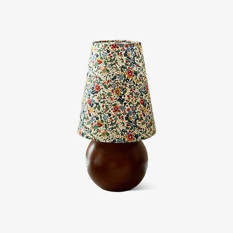 Floral shade lamp on a wood sphere base against a plain ground
