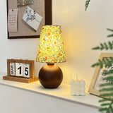 Floral shade lamp lit on a shelf beside a small flip calendar