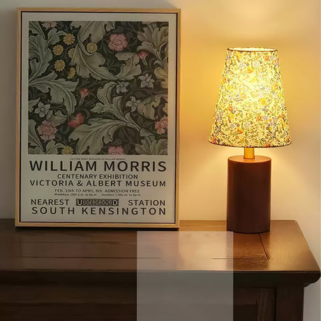 Floral shade lamp lit on a sideboard below a framed floral poster