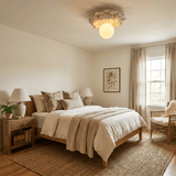 Carved floral ceiling light above a bed with linen covers and a wood nightstand