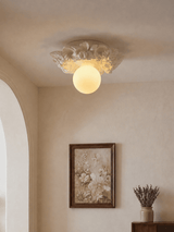 Carved floral ceiling light lit above a framed botanical print and a dresser