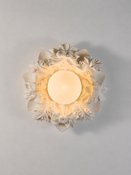 Carved floral ceiling light seen from below with the globe lit