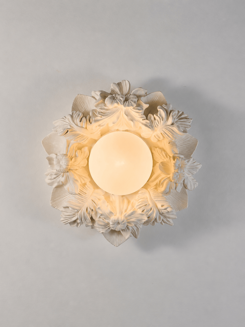 Carved floral ceiling light seen from below with the globe lit