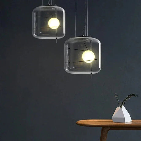 Two glass drum pendants lit against a dark wall above a side table