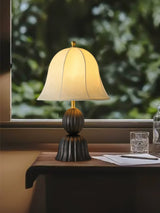Black based vintage table lamp on a table in front of a garden window