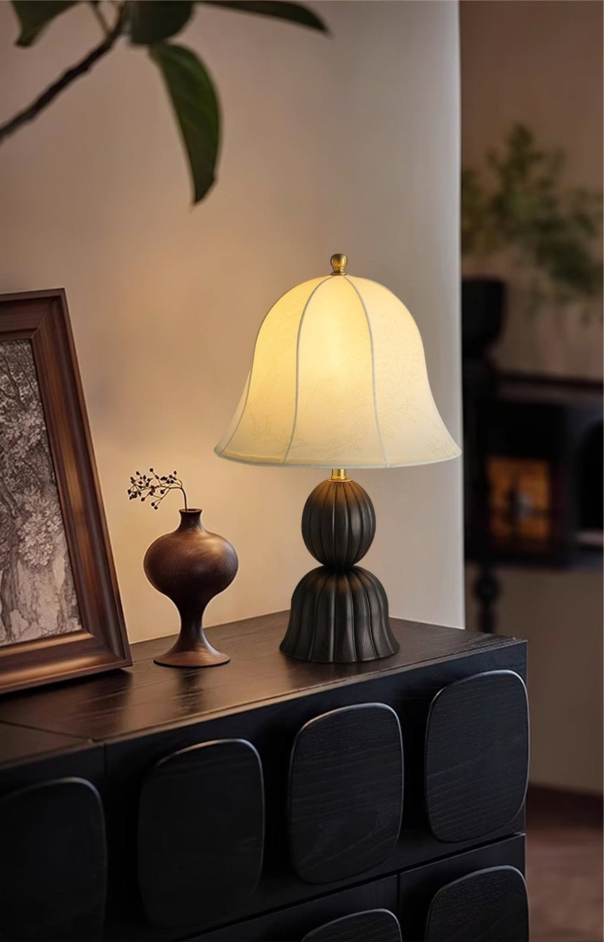 Black based vintage table lamp lit on a dark sideboard in a hallway