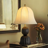 Black based vintage table lamp on a console beside a glass of flowers