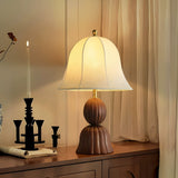Vintage table lamp lit on a sideboard beside a black candlestick