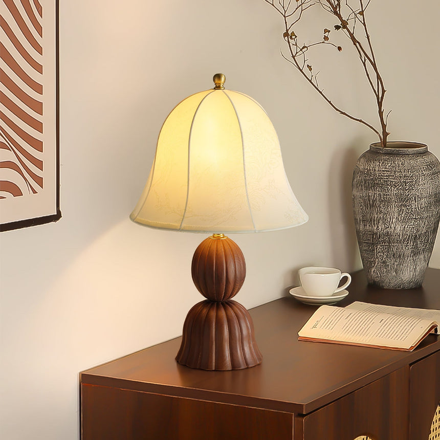 Vintage table lamp lit on a wooden chest beside a cup and an open book