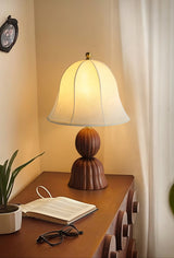 Vintage table lamp lit on a desk beside a book and a pair of glasses