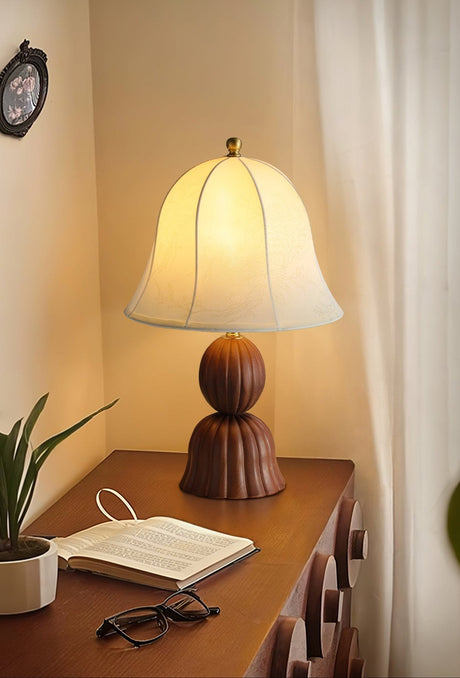 Vintage table lamp lit on a desk beside a book and a pair of glasses