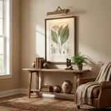 Bronze bar lit over a framed botanical print above a console with pots and books