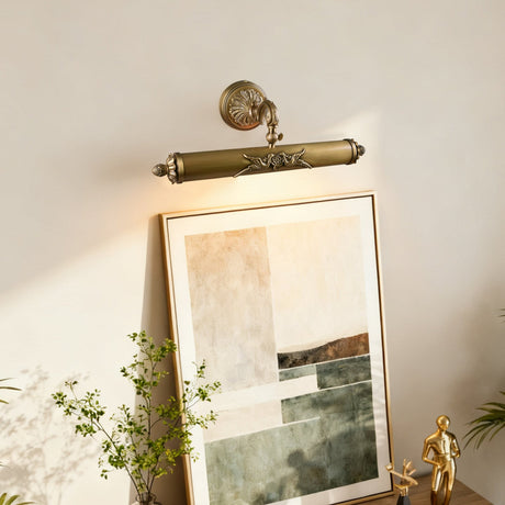 Scrolled brass bar lit over a framed canvas beside trailing green branches