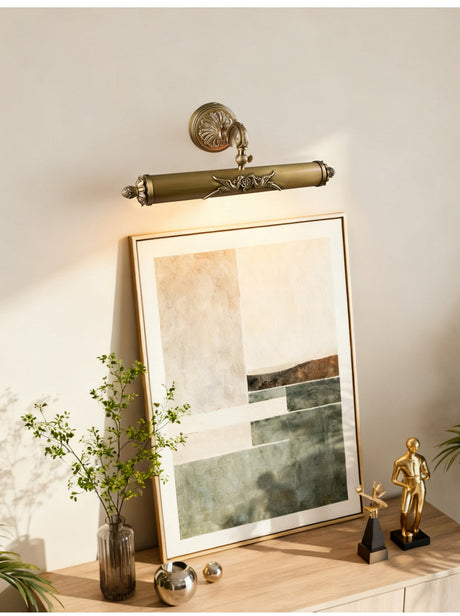 Scrolled brass bar lit over a framed canvas leaning above a console