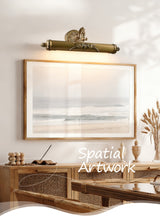 Scrolled brass bar lit over a framed canvas above a console in warm light