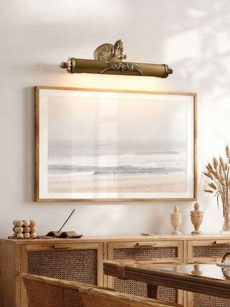 Scrolled brass bar lit over a framed seascape above a cane fronted console