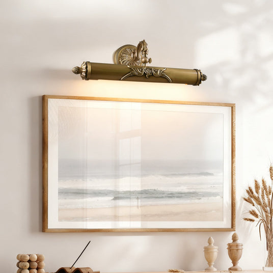 Scrolled brass bar lit above a framed seascape over a wood console
