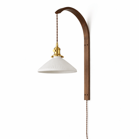 Ribbed white glass cone shade lit warm on the curved wood hook arm