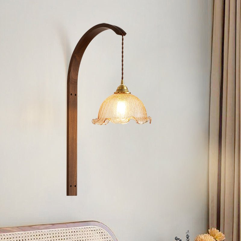 Scalloped amber glass shade lit on the wood arm above a cane headboard