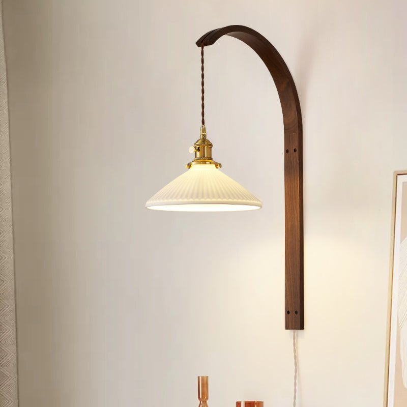 Wide white glass cone lit on the curved wood arm, the cord running down