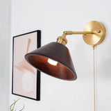 Walnut cone shade lit on a brass arm beside a framed print