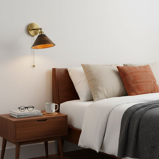 Walnut dome sconce lit above a nightstand beside a made bed