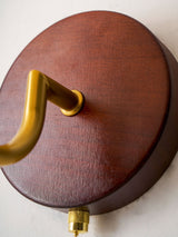Detail of the round dark wood backplate and the brass arm joint