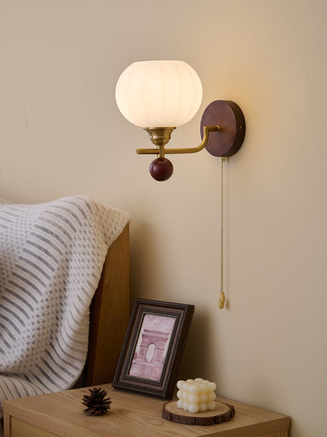 Ribbed glass sconce lit over a nightstand with a framed photograph