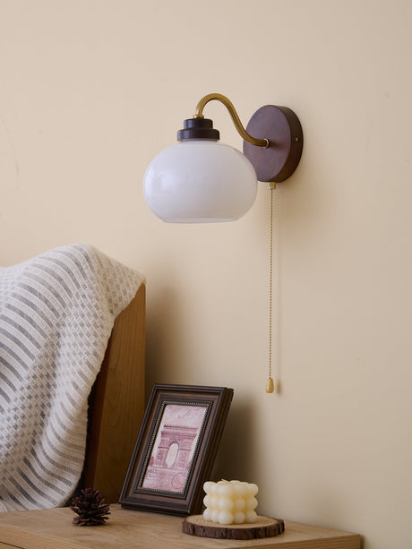 Rounded glass shade lit above a nightstand beside a pillow