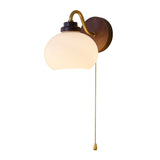Rounded white glass shade angled down on a brass gooseneck arm