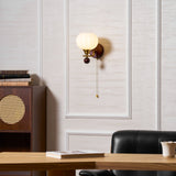 Ribbed glass sconce lit on a paneled wall above a desk and a chair