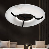 The lit ring in a dark living room above two pale sofas and a low table