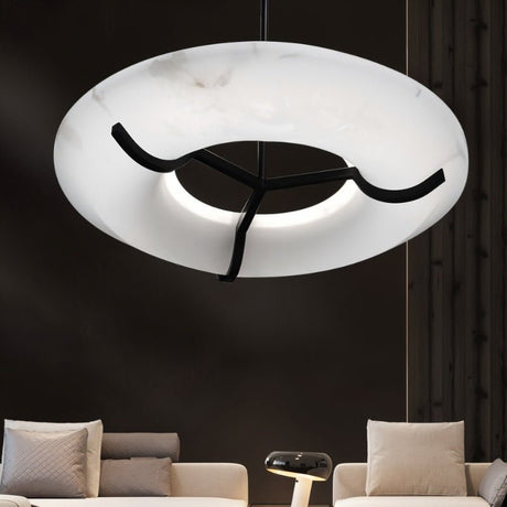 The lit ring in a dark living room above two pale sofas and a low table