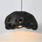 Black perforated dome shade photographed against a pale ground